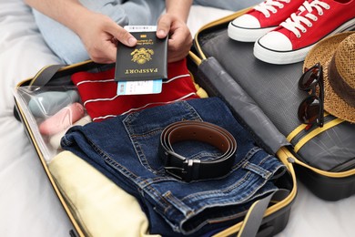 Man packing suitcase for trip on bed, closeup