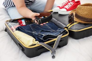 Photo of Man packing suitcase for trip on bed, closeup