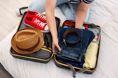 Man packing suitcase for trip on bed, closeup