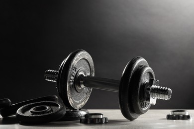 Photo of Barbell and parts of one on light table against dark background