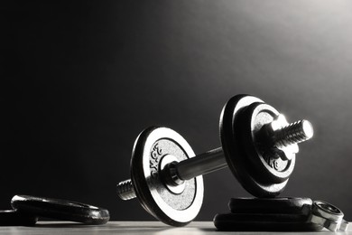 Photo of Barbell and parts of one on light table against dark background