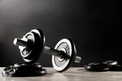 Photo of Barbell and parts of one on light table against dark background