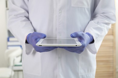 Photo of Doctor in gloves with tablet indoors, closeup