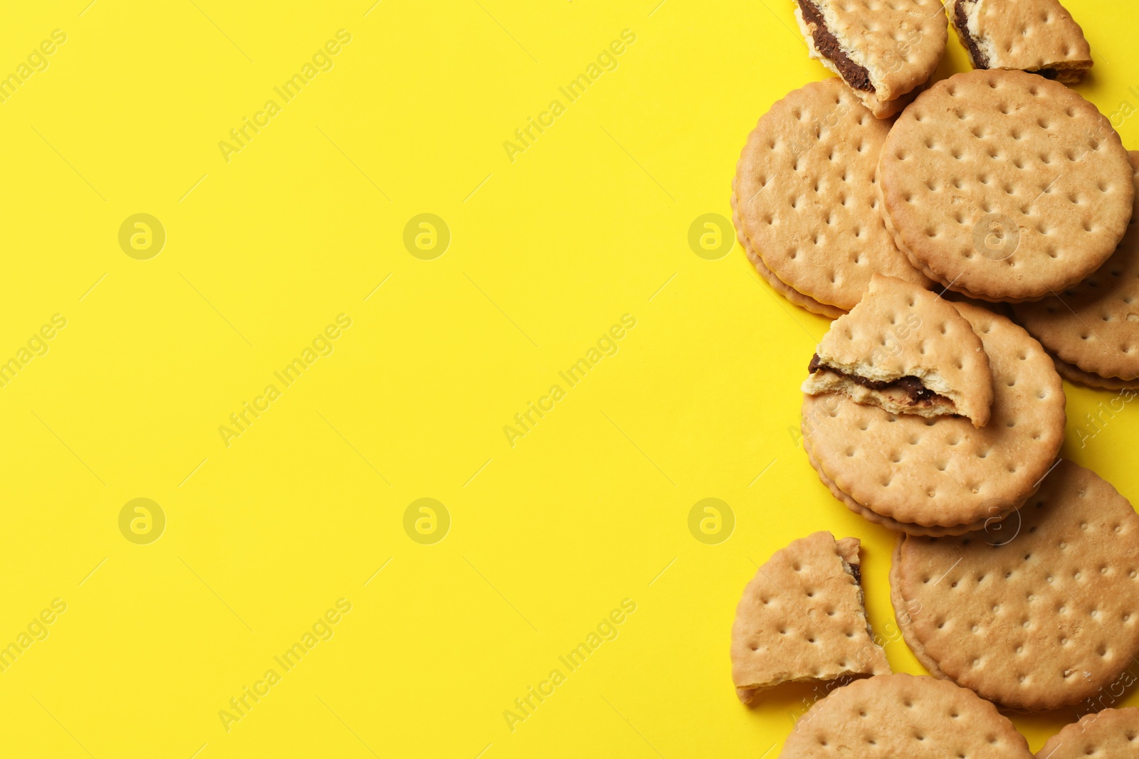 Photo of Tasty sandwich cookies on yellow background, top view. Space for text