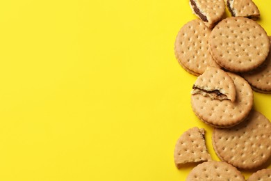 Photo of Tasty sandwich cookies on yellow background, top view. Space for text