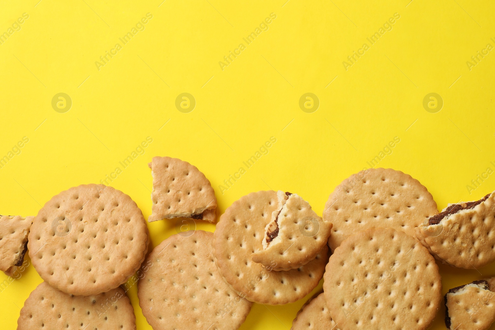 Photo of Tasty sandwich cookies on yellow background, top view. Space for text