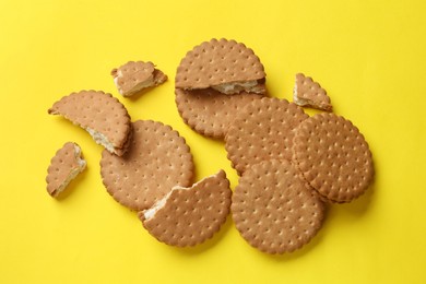 Photo of Tasty sandwich cookies on yellow background, top view