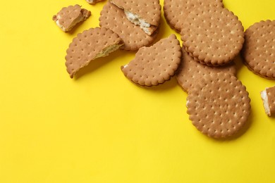 Tasty sandwich cookies on yellow background, top view. Space for text