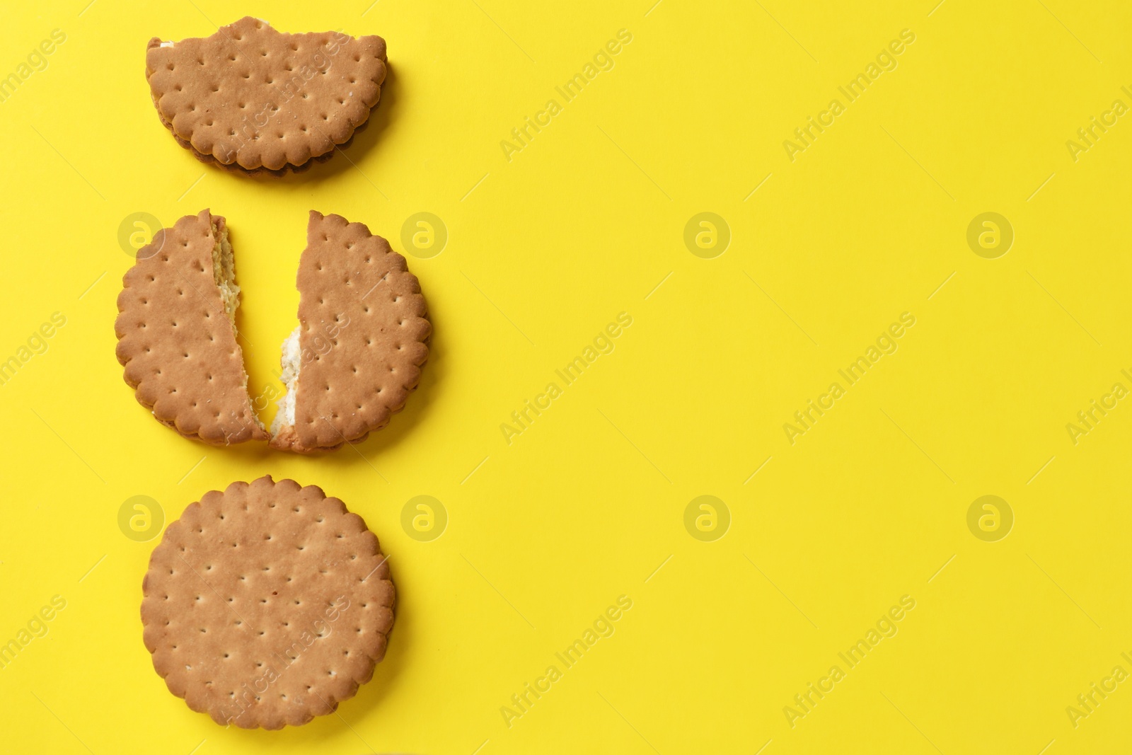 Photo of Tasty sandwich cookies on yellow background, top view. Space for text