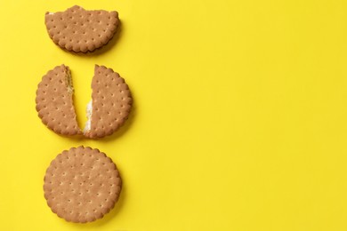 Tasty sandwich cookies on yellow background, top view. Space for text