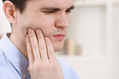 Photo of Man suffering from toothache at home, space for text