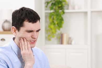 Photo of Man suffering from toothache at home, space for text