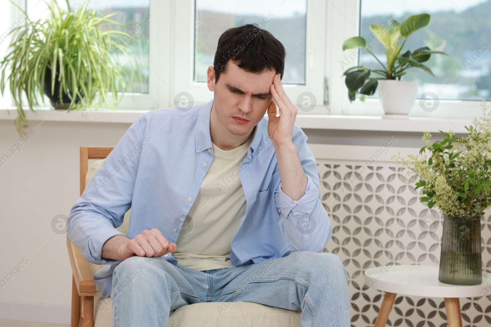 Photo of Sad man suffering from headache at home