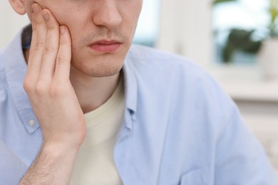 Photo of Man suffering from toothache at home, closeup