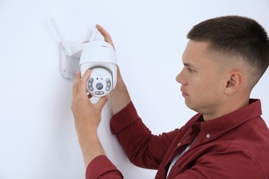 Technician installing CCTV camera on wall indoors