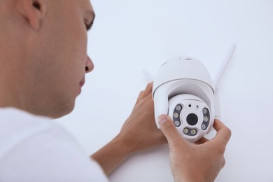 Technician installing CCTV camera on wall indoors, closeup