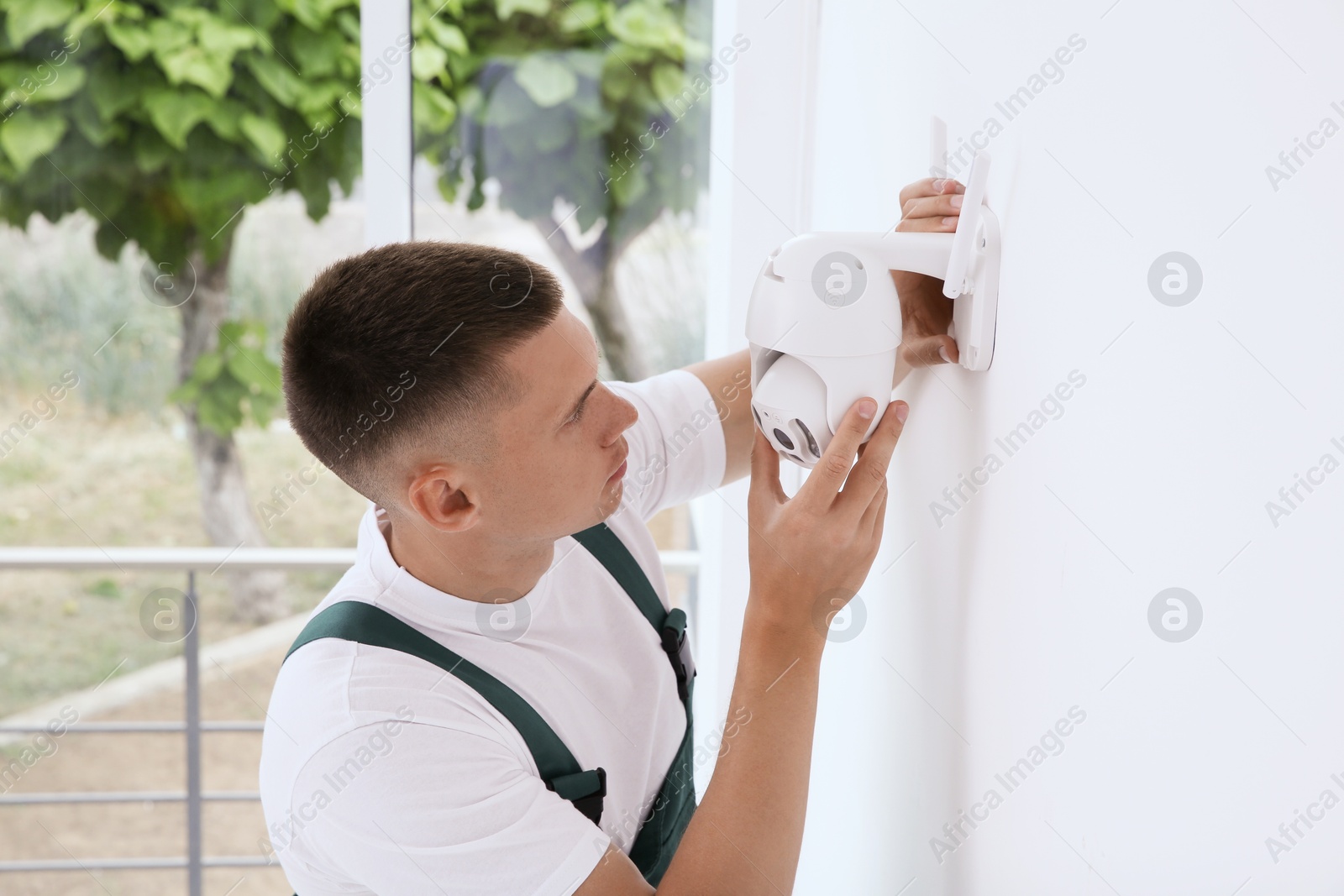 Photo of Technician installing CCTV camera on wall indoors