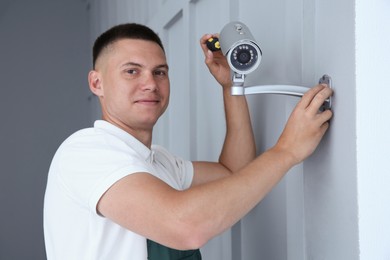 Technician installing CCTV camera on wall indoors