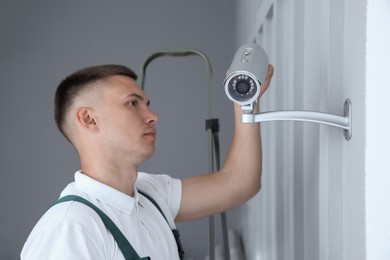 Technician installing CCTV camera on wall indoors