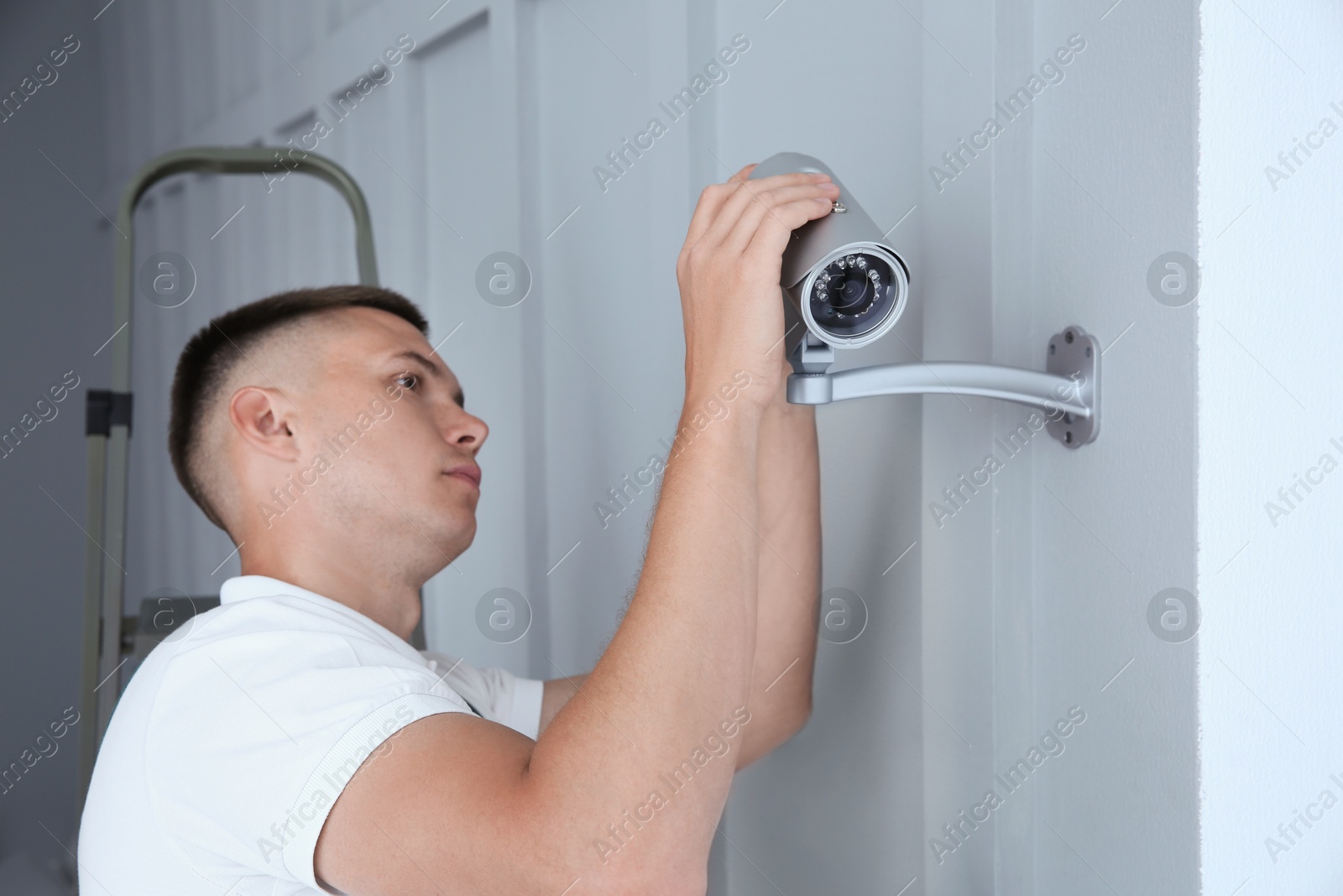 Photo of Technician installing CCTV camera on wall indoors