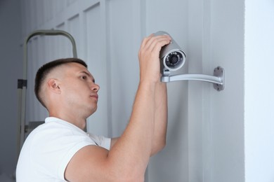 Technician installing CCTV camera on wall indoors