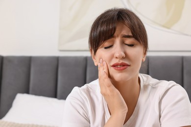 Photo of Upset young woman suffering from toothache indoors
