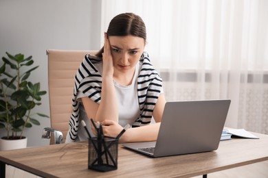 Photo of Embarrassed woman at wooden table with laptop in office