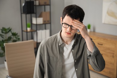 Photo of Embarrassed young man in glasses in office