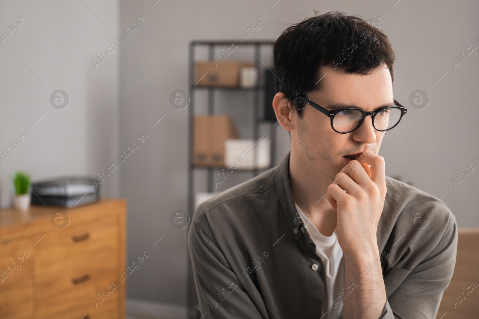 Photo of Embarrassed young man in glasses in office, space for text