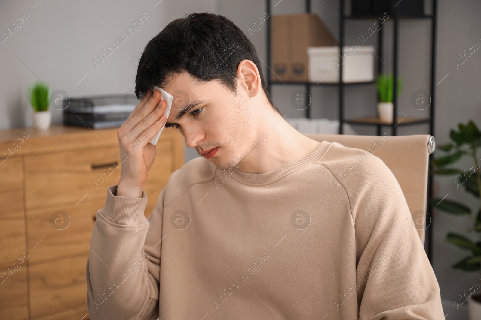 Photo of Embarrassed young man with tissue in office