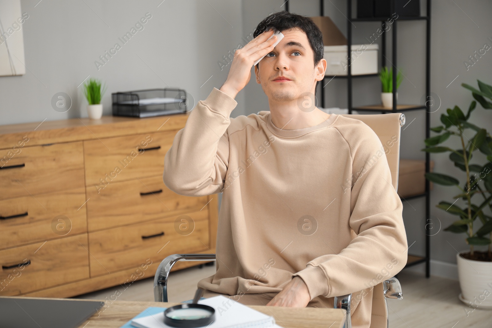 Photo of Embarrassed man with tissue at table in office