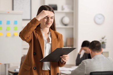 Photo of Woman with clipboard feeling embarrassed during business meeting in office