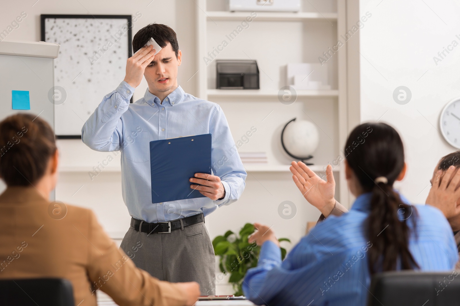 Photo of Man with clipboard feeling embarrassed during business meeting in office