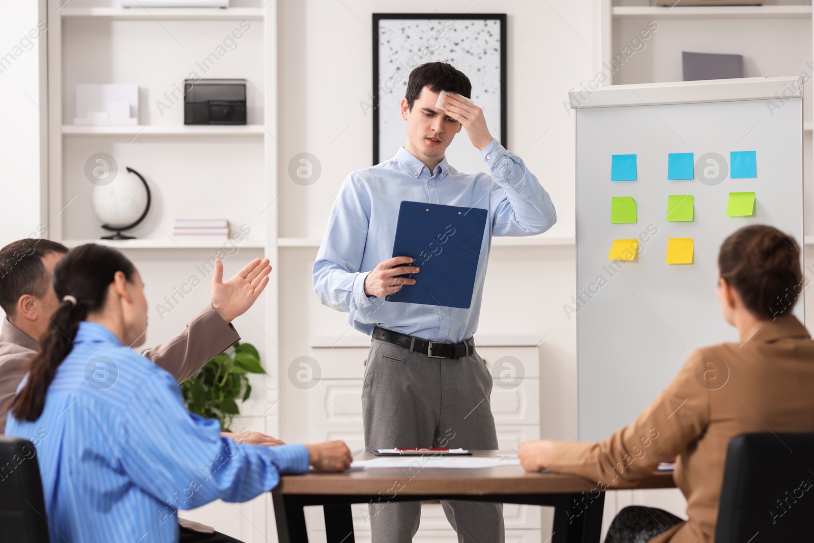 Photo of Man with clipboard feeling embarrassed during business meeting in office