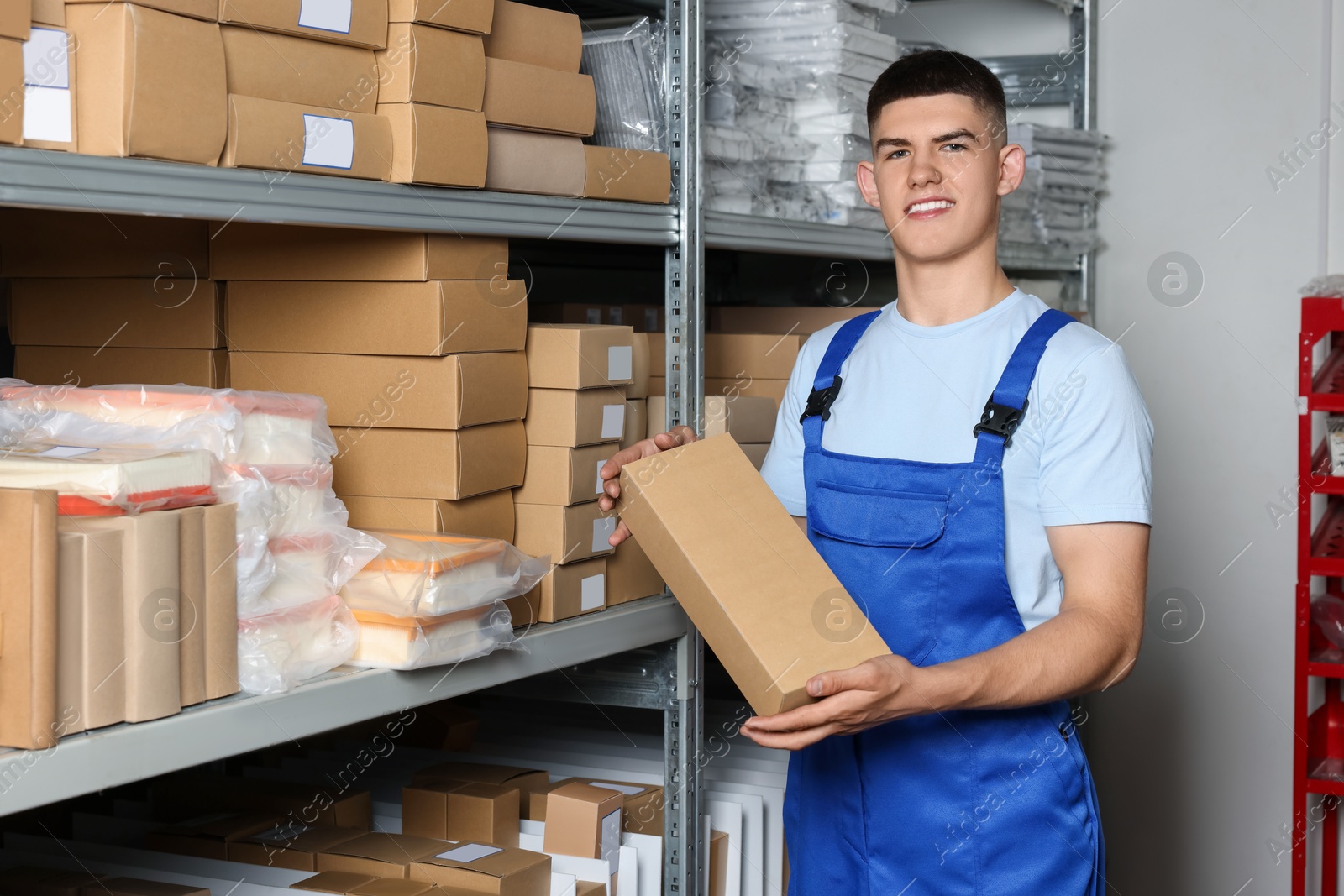 Photo of Smiling young man with many cardboard boxes in auto store