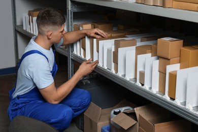 Photo of Young man with many cardboard boxes in auto store