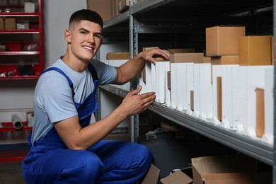 Smiling young man near many cardboard boxes in auto store