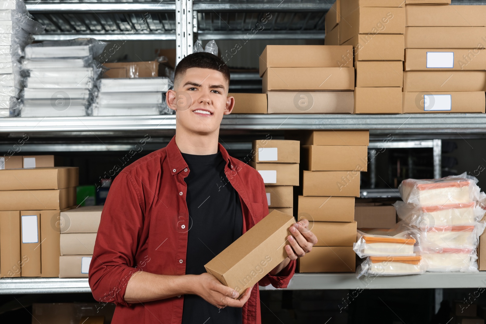 Photo of Smiling young man with cardboard boxes in auto store