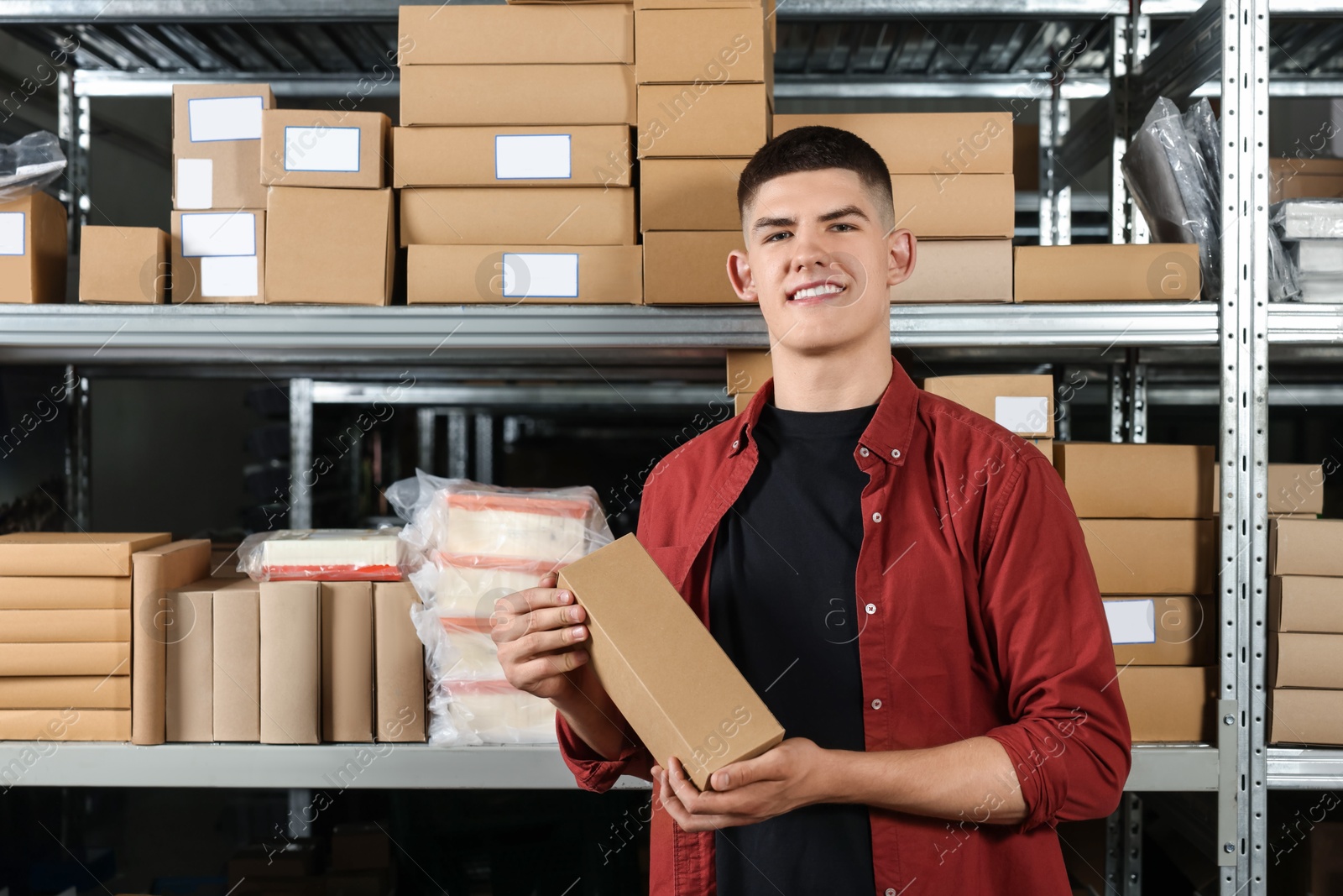 Photo of Smiling young man with cardboard boxes in auto store