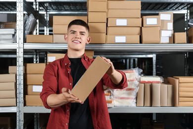 Smiling young man with cardboard boxes in auto store