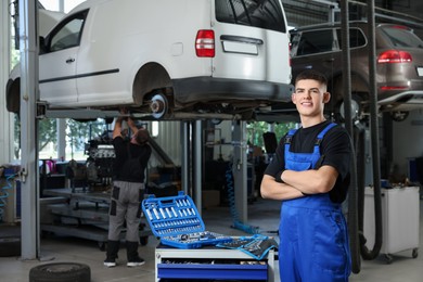 Young auto mechanic with different tools at automobile repair shop