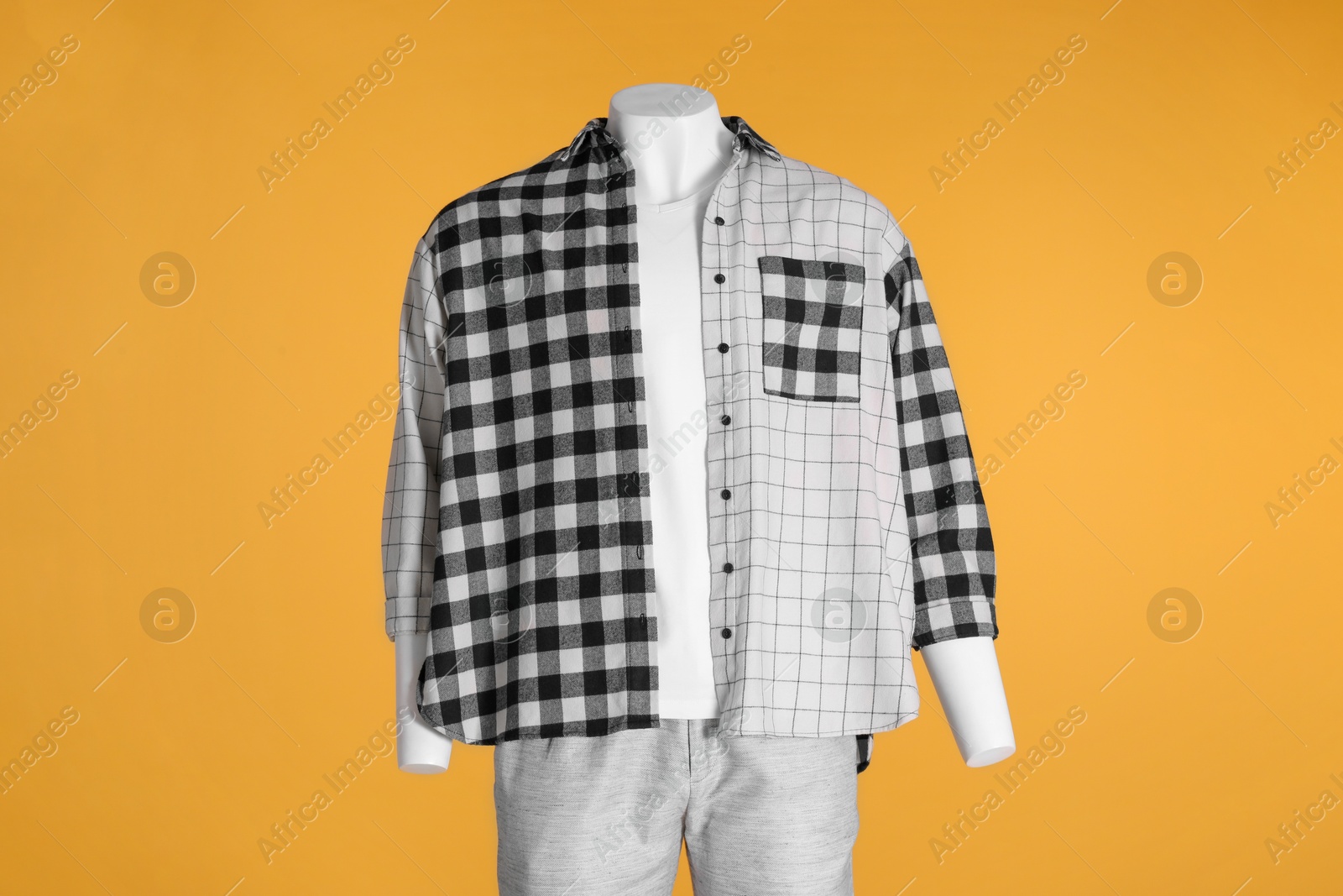 Photo of Male mannequin dressed in white t-shirt, stylish checkered shirt and pants on orange background