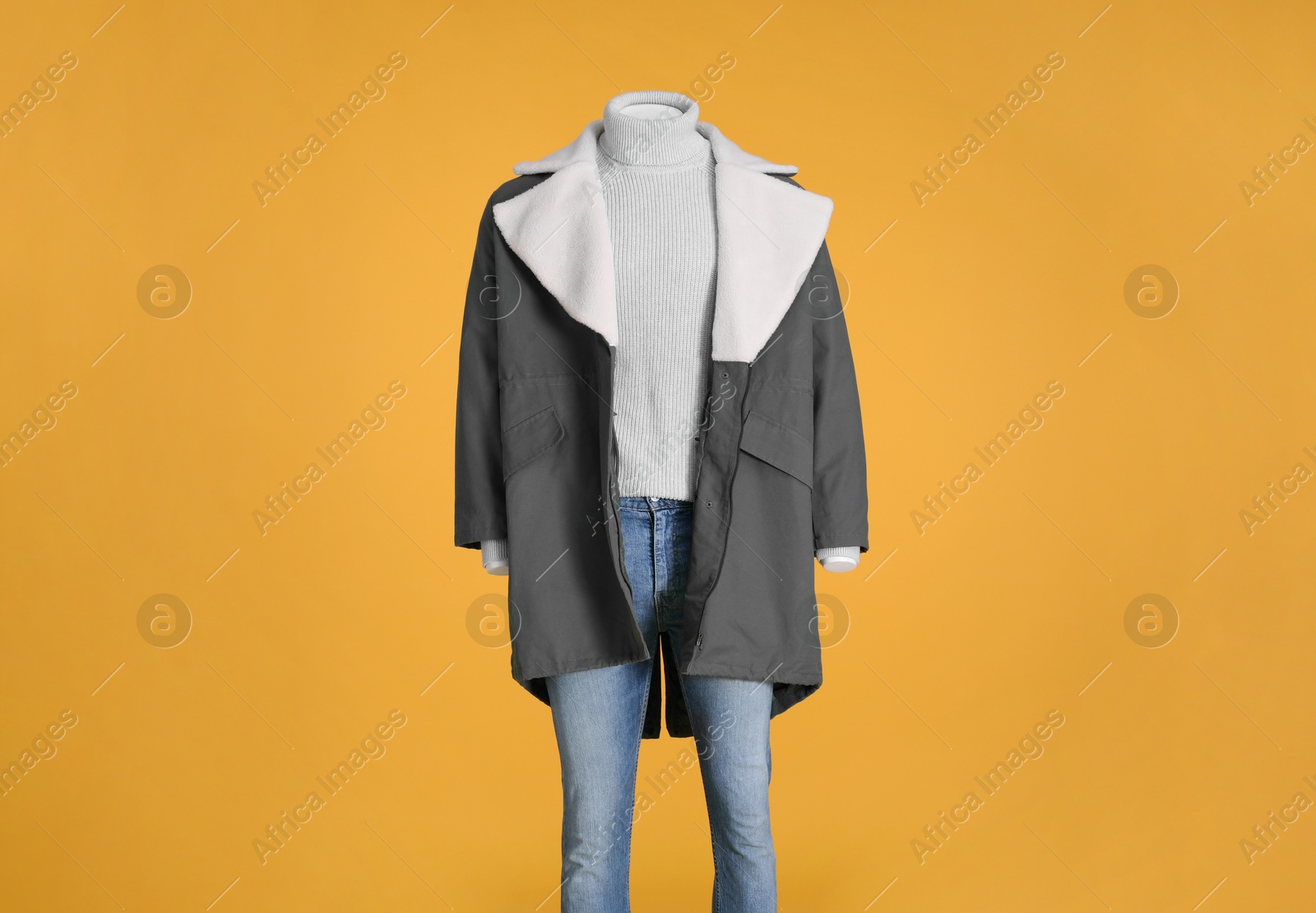 Photo of Female mannequin dressed in stylish jacket, turtleneck and jeans on orange background