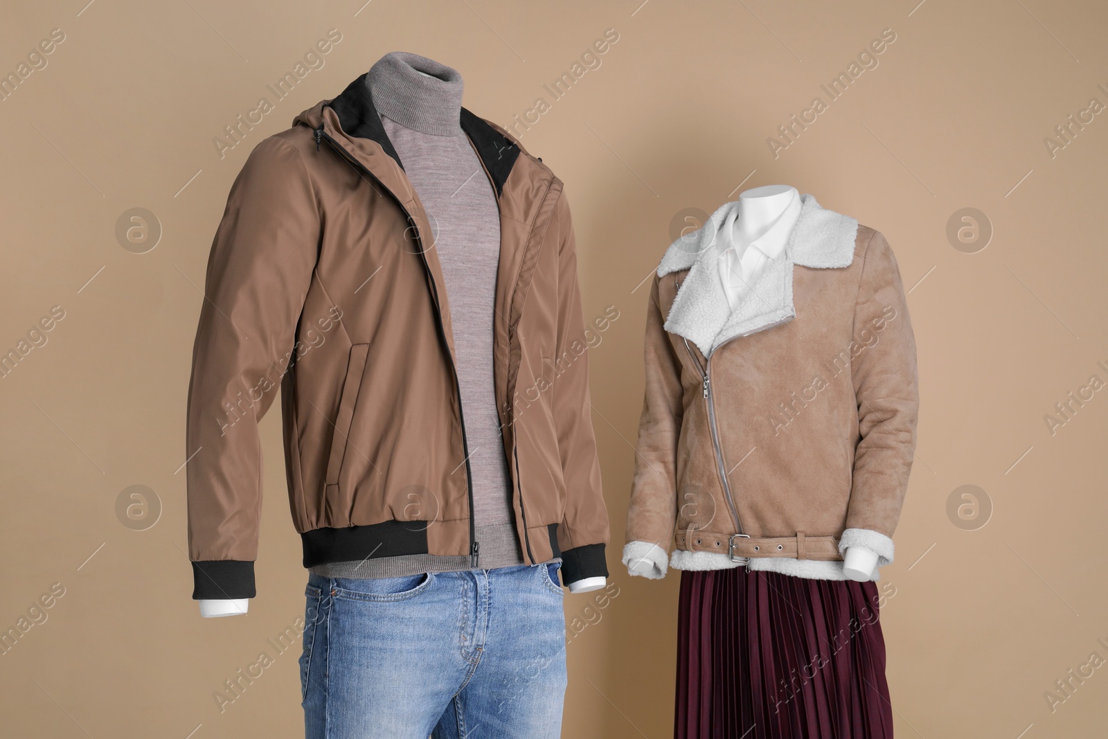 Photo of Female and male mannequins dressed in different clothes on beige background. Stylish outfits