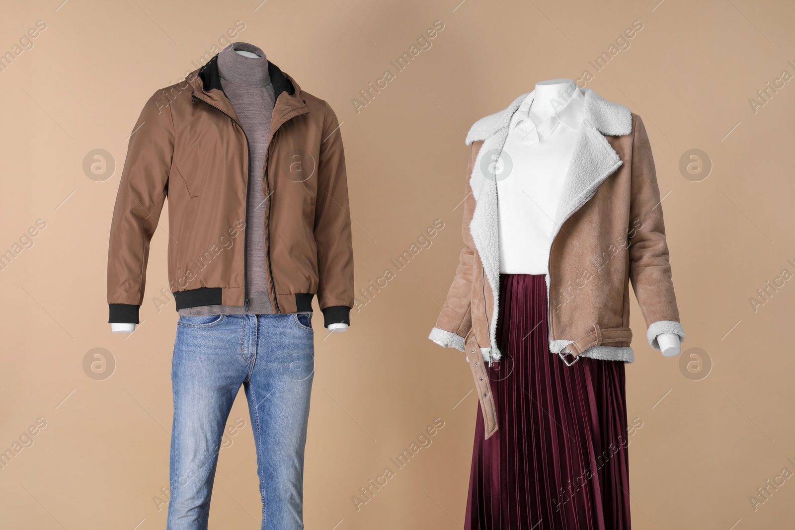 Photo of Female and male mannequins dressed in different clothes on beige background. Stylish outfits