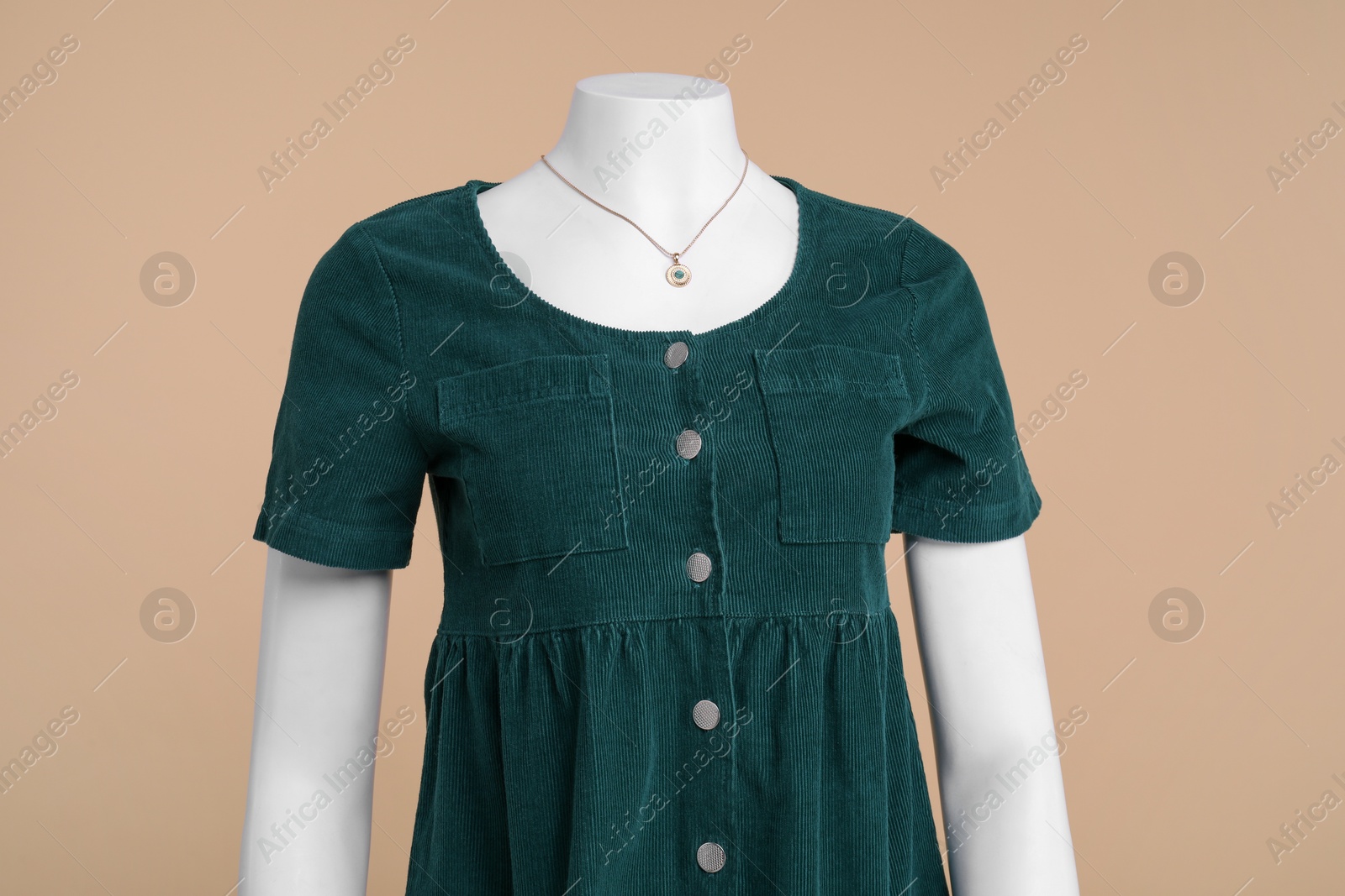 Photo of Female mannequin with necklace dressed in stylish dark green dress on beige background