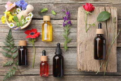 Photo of Aromatherapy. Different essential oils and flowers on wooden table, flat lay