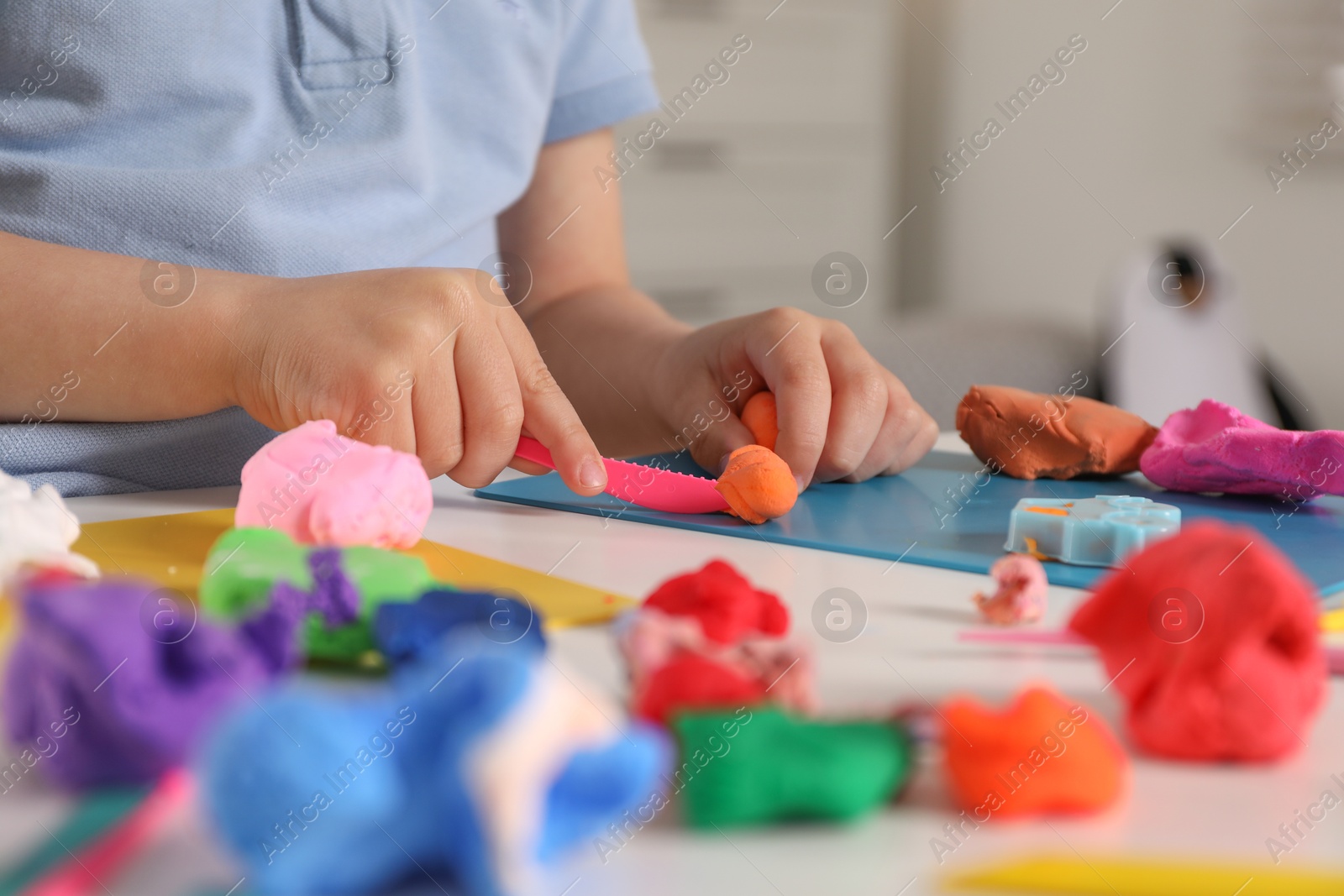 Photo of Little boy sculpting with play dough at table indoors, closeup