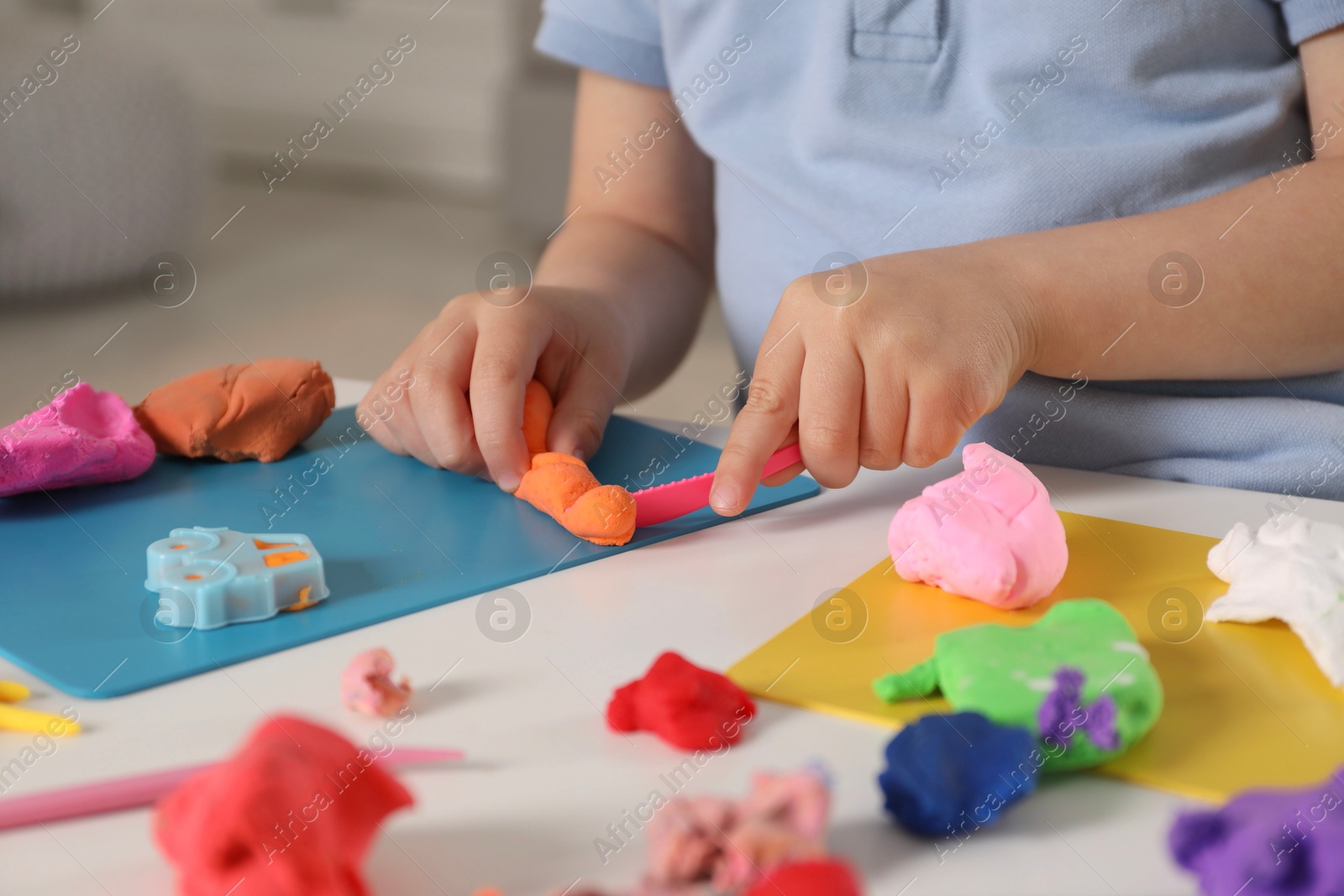 Photo of Little boy sculpting with play dough at table indoors, closeup