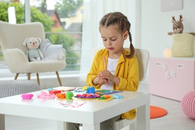 Little girl sculpting with play dough at table in kindergarten